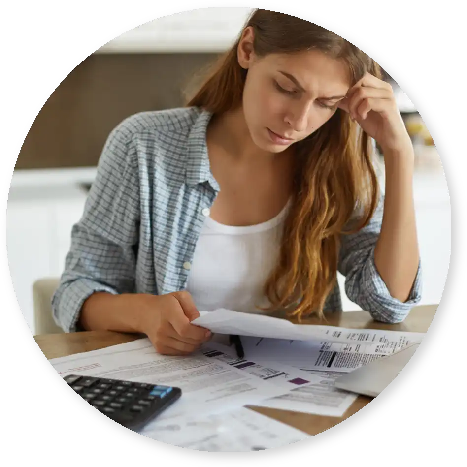 A young woman looks over bills and paperwork at her kitchen table
