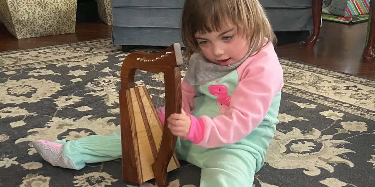 A young girl playing a small harp she received through Bringing Holiday Cheer