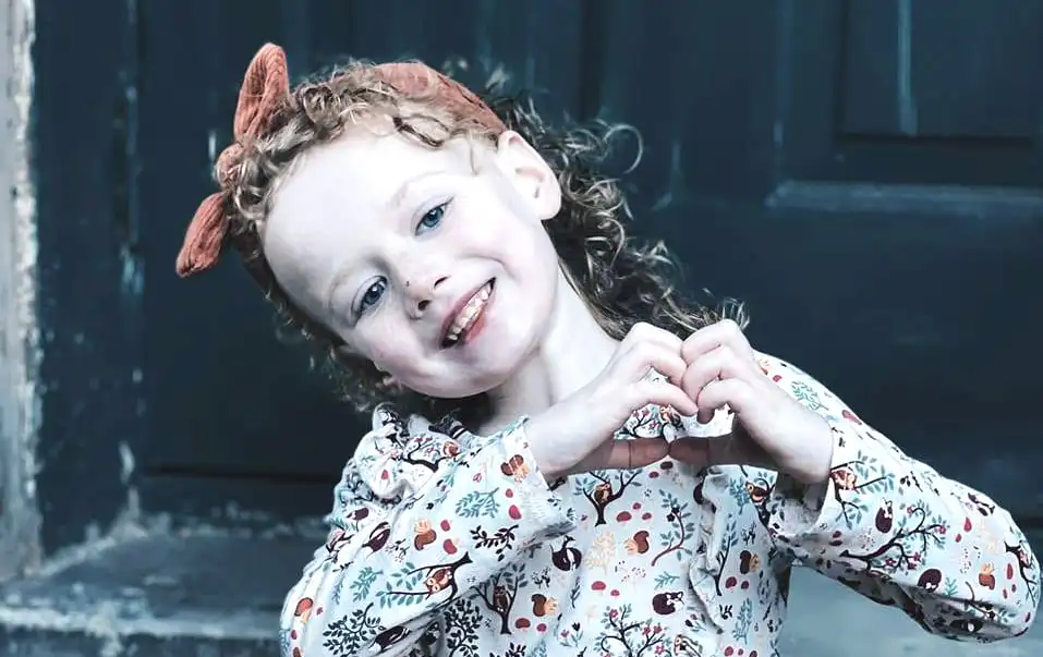 Smiling girl making a heart shape with her hands