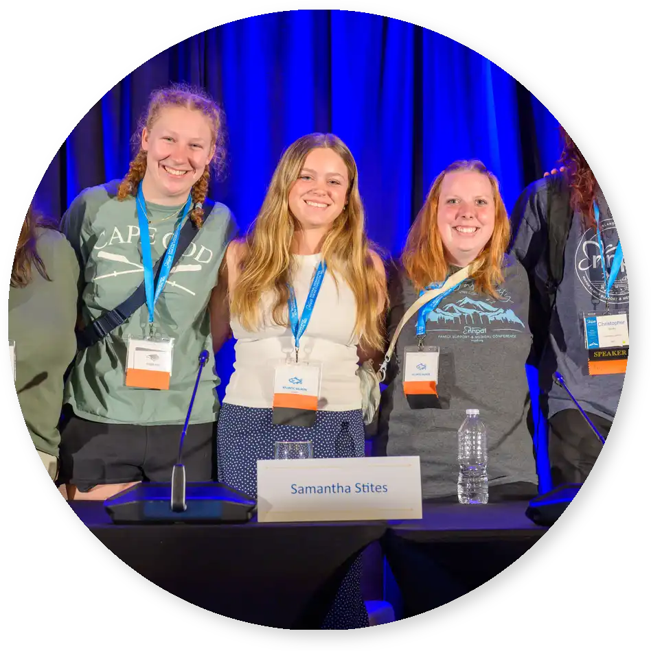 Young adult siblings smile together on stage at the NNPDF Family Conference